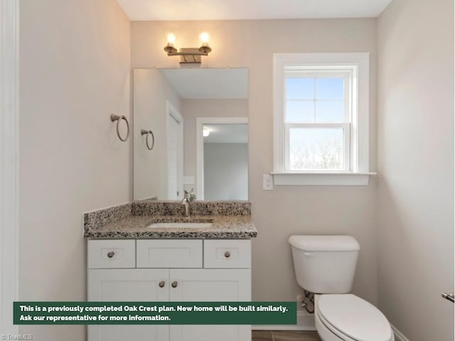 half bath featuring vanity, toilet, and baseboards