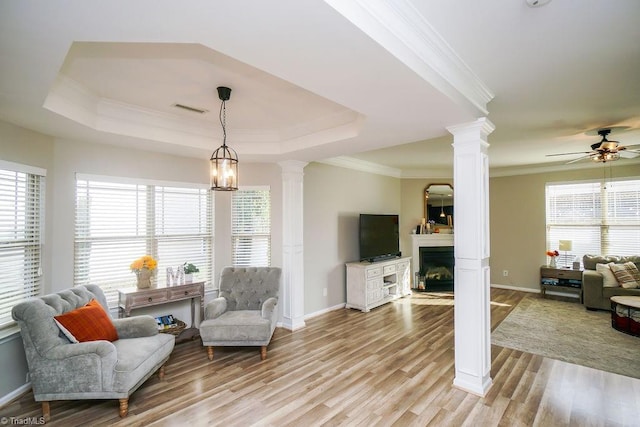 living room with plenty of natural light, crown molding, light wood-type flooring, and ceiling fan with notable chandelier