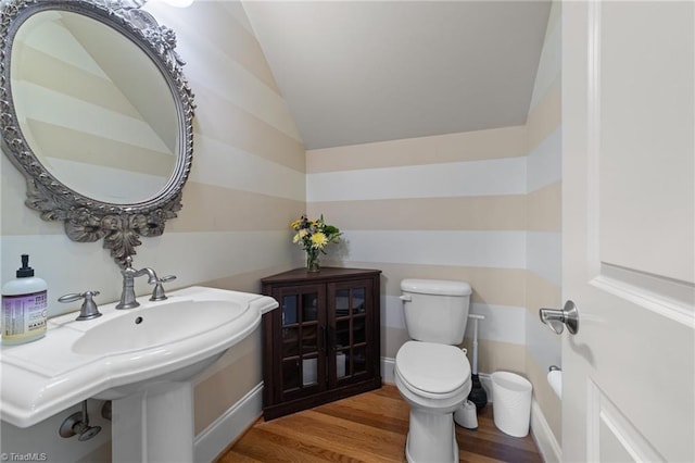 bathroom with toilet, wood finished floors, and lofted ceiling