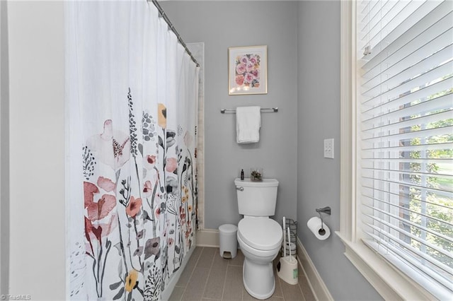 bathroom with baseboards, tile patterned floors, toilet, and a shower with curtain