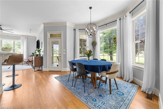 dining room featuring visible vents, light wood finished floors, crown molding, and a healthy amount of sunlight