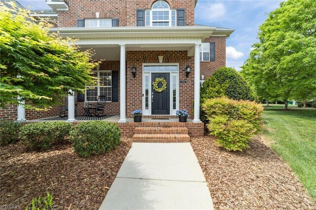 entrance to property with brick siding and a porch