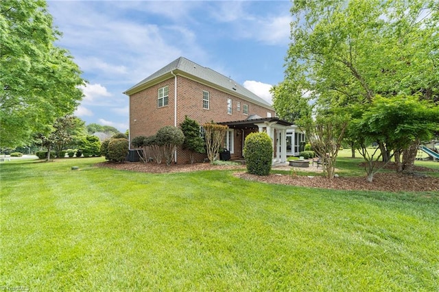 back of house with brick siding and a yard