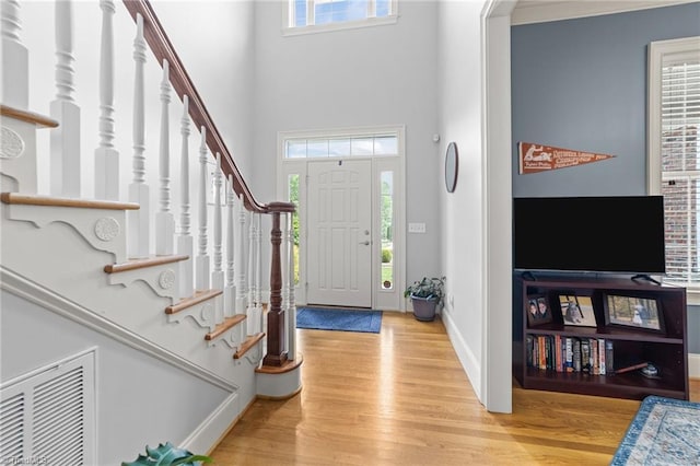 foyer entrance with visible vents, wood finished floors, and stairway