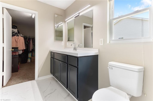 3602 Turquoise Dr, Durham, NC 27703 - bathroom featuring vanity, toilet, marble finish floors, a spacious closet, and baseboards