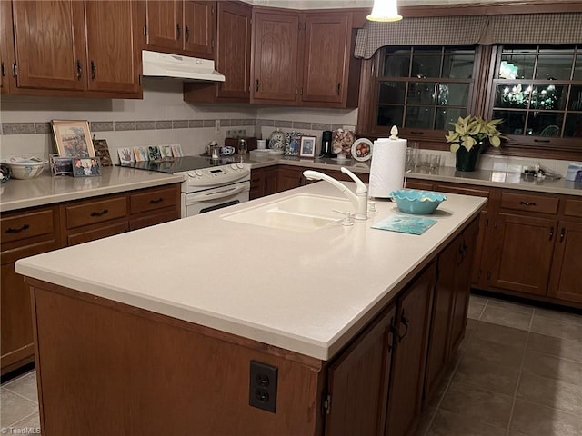 kitchen featuring a kitchen island with sink, sink, and white range with electric cooktop