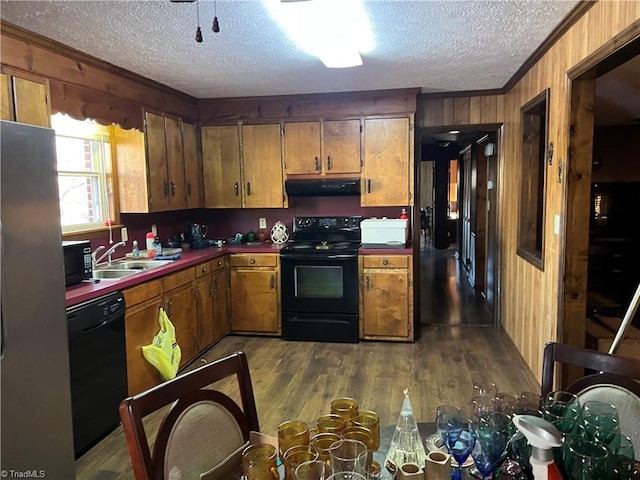 kitchen with sink, extractor fan, ornamental molding, wooden walls, and black appliances