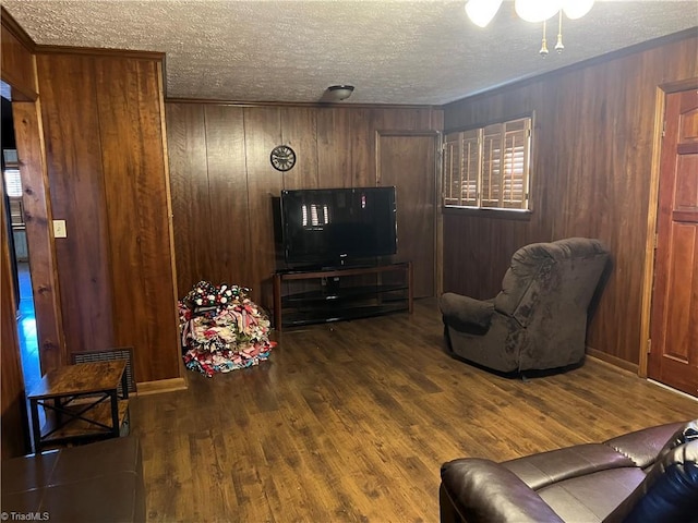 living room with a textured ceiling, dark hardwood / wood-style flooring, and wood walls