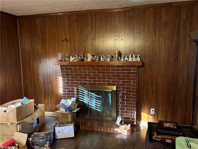 living room with hardwood / wood-style flooring, wooden walls, a brick fireplace, and a textured ceiling