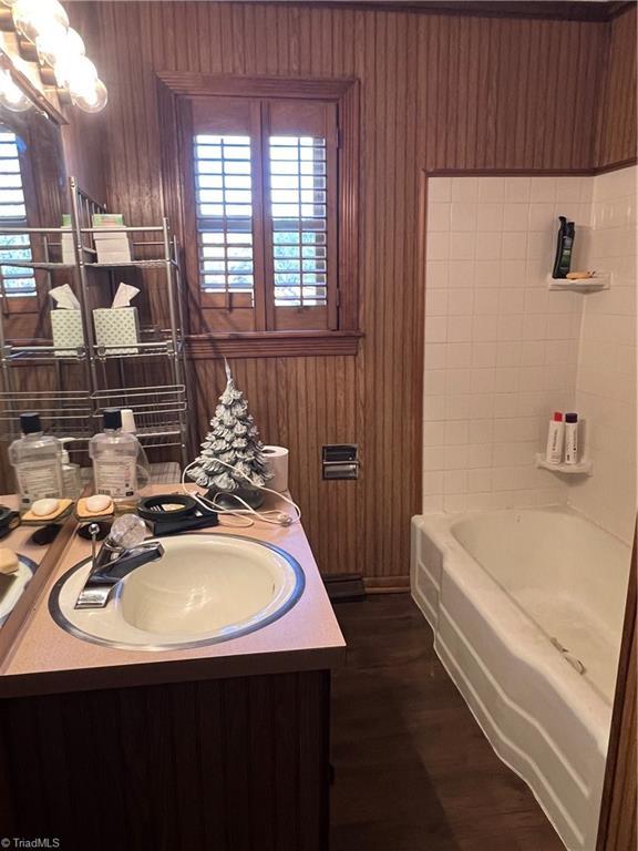 bathroom with vanity, wooden walls, a wealth of natural light, and an inviting chandelier