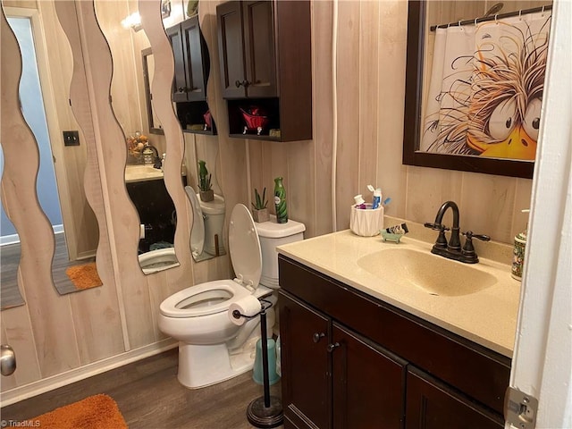 bathroom featuring vanity, hardwood / wood-style flooring, toilet, and wooden walls