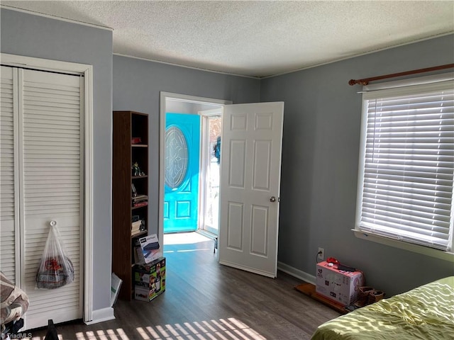 bedroom featuring dark hardwood / wood-style flooring, a textured ceiling, and a closet