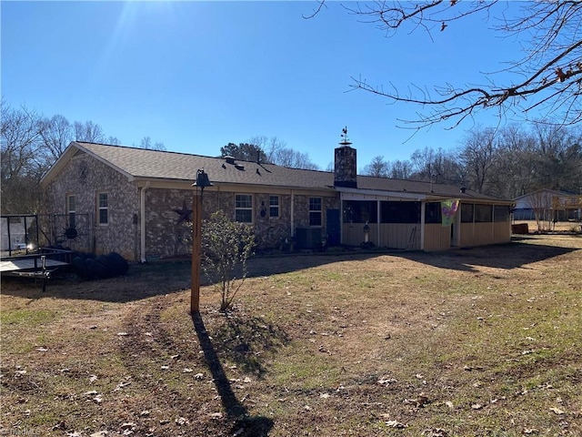 rear view of house featuring a lawn, central AC, and a sunroom