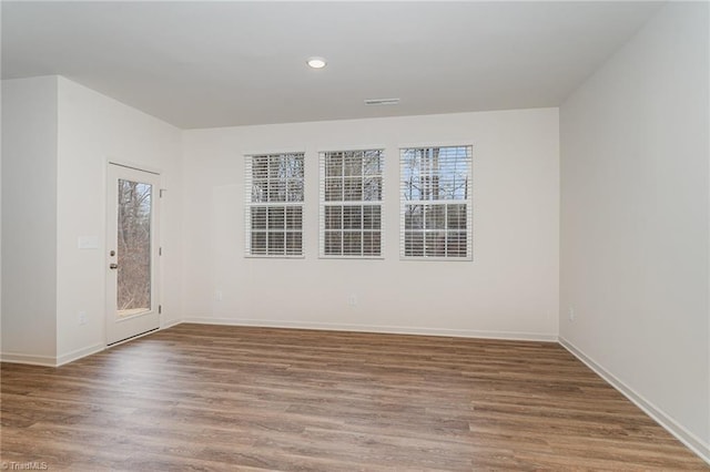 spare room featuring a healthy amount of sunlight and wood-type flooring