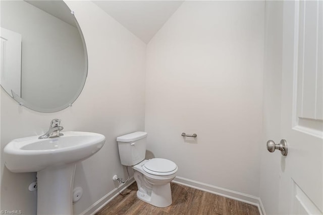 bathroom with wood-type flooring, vaulted ceiling, sink, and toilet