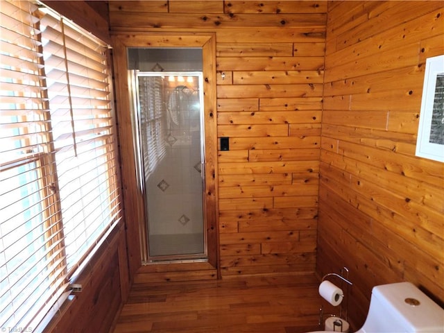 bathroom with toilet, walk in shower, and wood walls