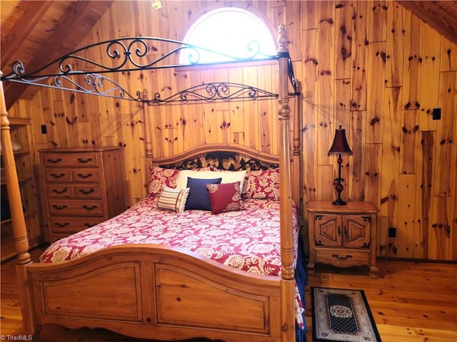 bedroom featuring wood walls, wood-type flooring, and vaulted ceiling