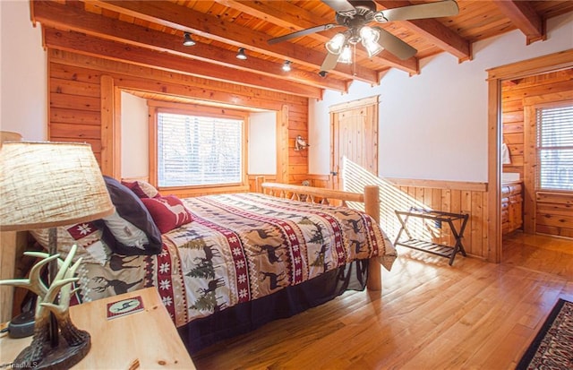 bedroom with multiple windows, ceiling fan, wooden ceiling, and wood walls