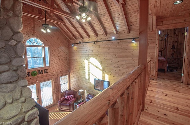 corridor with wooden ceiling, high vaulted ceiling, wooden walls, light wood-type flooring, and beam ceiling