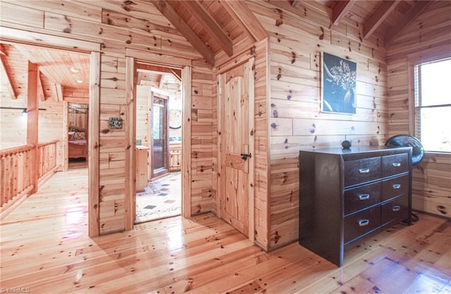 corridor with lofted ceiling with beams and wood walls