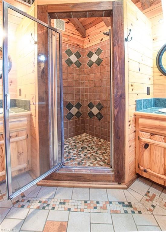 bathroom featuring vanity, wood walls, and a shower with shower door