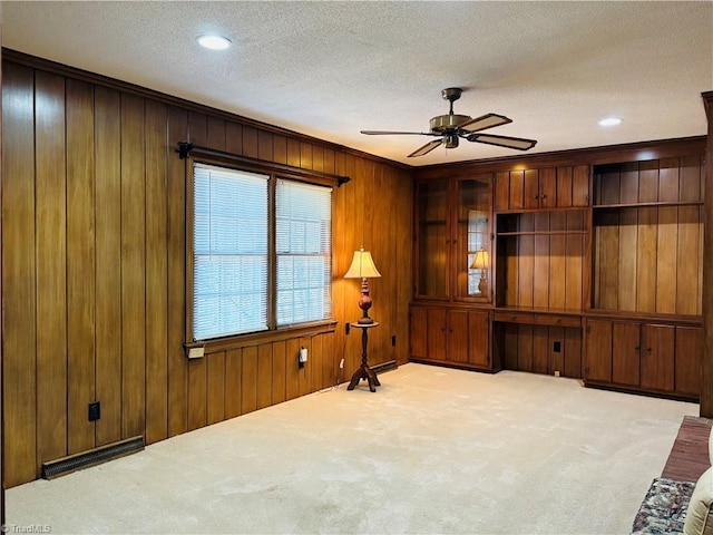 living room with a textured ceiling, ceiling fan, wood walls, carpet flooring, and visible vents