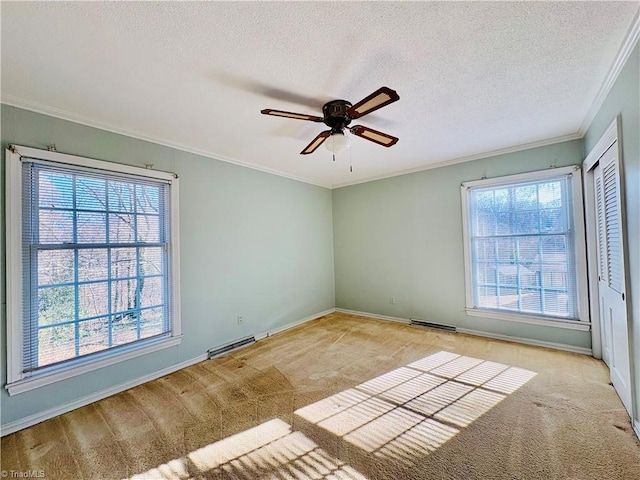 carpeted empty room featuring a ceiling fan, visible vents, crown molding, and a textured ceiling