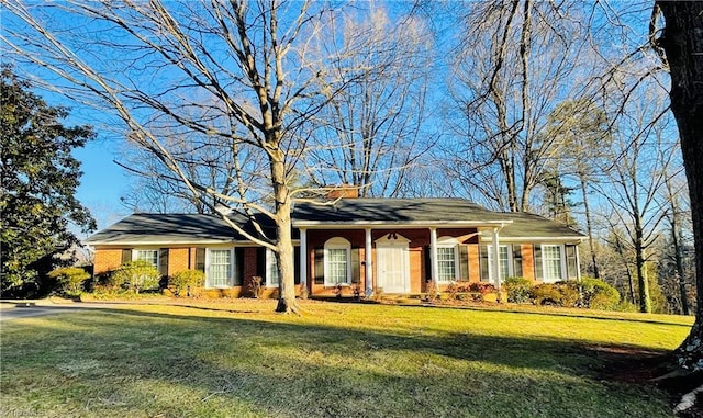 ranch-style house with a chimney, a front lawn, and brick siding