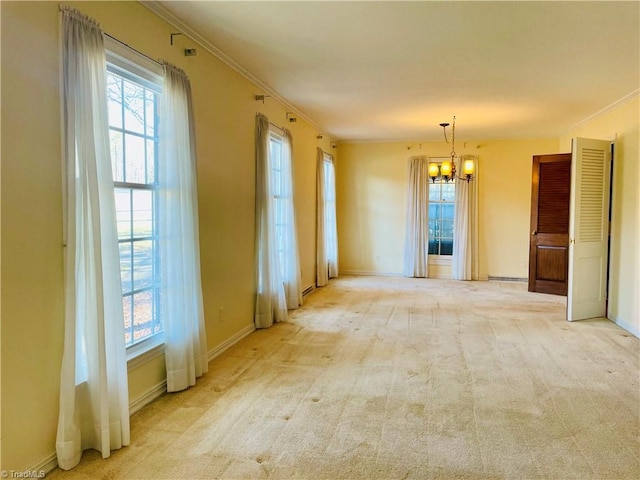 carpeted empty room with crown molding, baseboards, and a notable chandelier