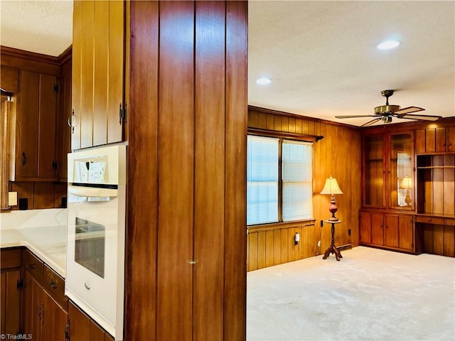 kitchen with light countertops, oven, wooden walls, and carpet flooring