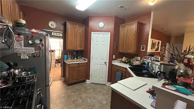 kitchen with kitchen peninsula, stainless steel fridge, and sink