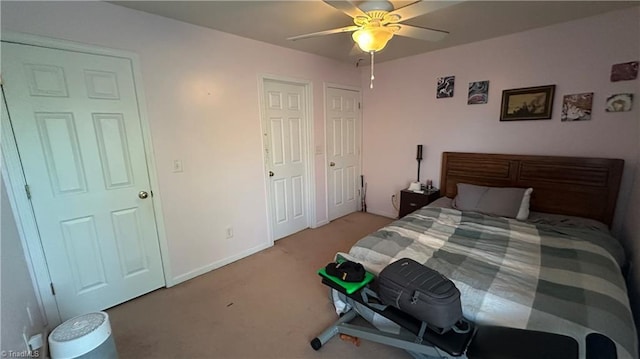 carpeted bedroom with ceiling fan and two closets