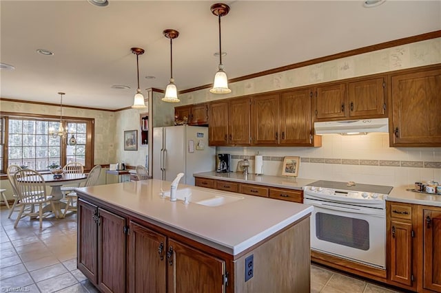 kitchen featuring white appliances, a center island with sink, light countertops, under cabinet range hood, and a sink