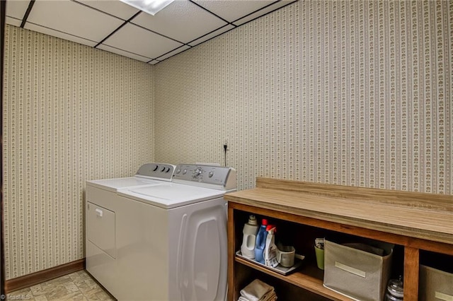 laundry room with laundry area, stone finish floor, washer and clothes dryer, and wallpapered walls