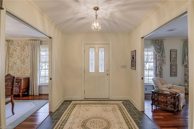 entryway featuring an inviting chandelier, plenty of natural light, baseboards, and crown molding