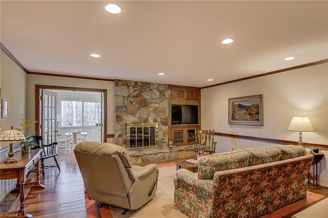 living room with light wood finished floors, a wainscoted wall, ornamental molding, a fireplace, and recessed lighting