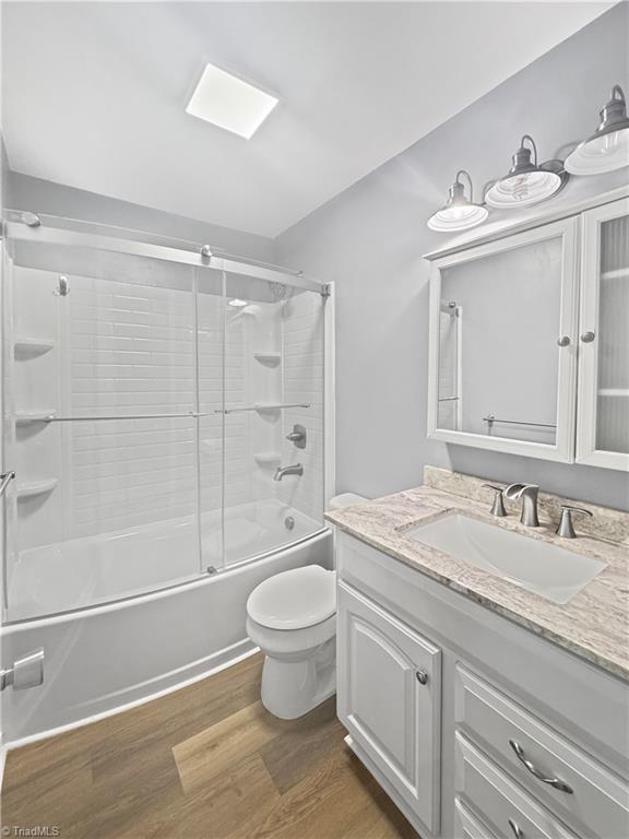 964 Mountain View Rd, North Wilkesboro, NC 28659 - full bath with wood finished floors, toilet, enclosed tub / shower combo, and vanity