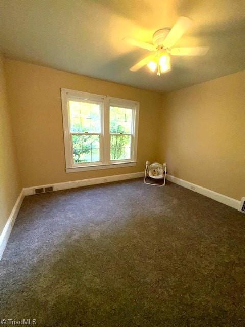 unfurnished room with baseboards, ceiling fan, dark colored carpet, and visible vents