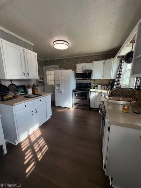kitchen featuring white cabinets, appliances with stainless steel finishes, a sink, light countertops, and dark wood-type flooring