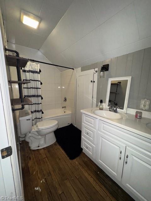bathroom featuring vanity, toilet, shower / bath combo with shower curtain, hardwood / wood-style floors, and lofted ceiling