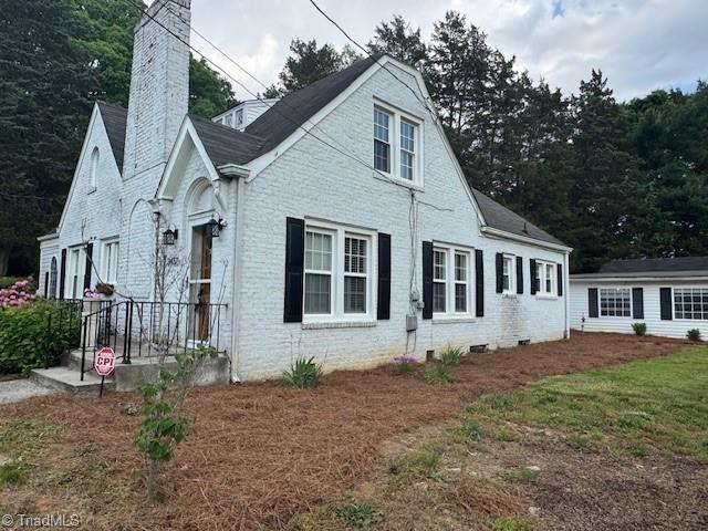 view of front of house with brick siding and a chimney