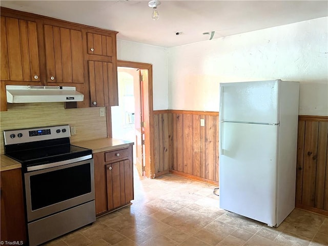 1716 US Highway 220, Stokesdale, NC 27357 - kitchen with under cabinet range hood, freestanding refrigerator, stainless steel electric stove, brown cabinetry, and a wainscoted wall