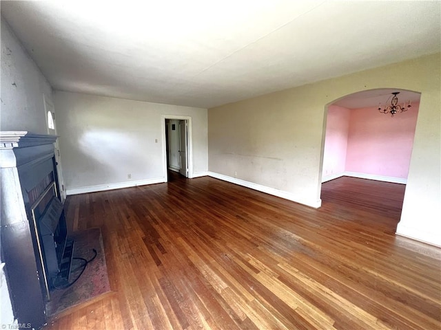 1716 US Highway 220, Stokesdale, NC 27357 - unfurnished living room with wood-type flooring, a fireplace with raised hearth, arched walkways, a chandelier, and baseboards