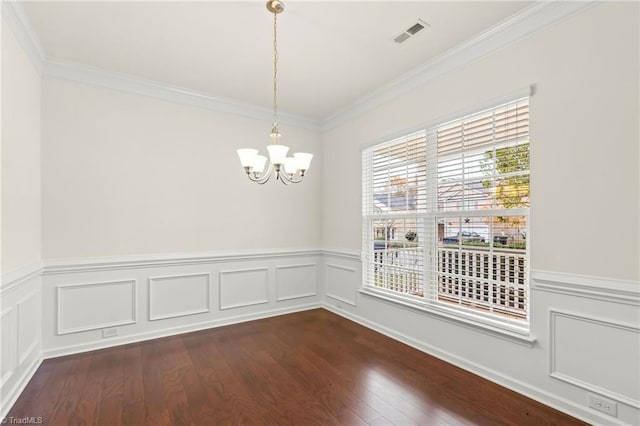 empty room featuring an inviting chandelier, ornamental molding, and dark wood-type flooring