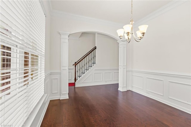 unfurnished dining area featuring crown molding, a notable chandelier, dark hardwood / wood-style floors, and decorative columns