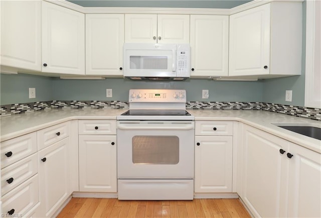 kitchen with white appliances, decorative backsplash, light countertops, white cabinets, and light wood-style floors