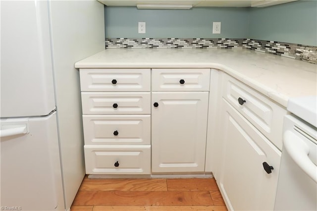 kitchen with backsplash, white cabinets, and freestanding refrigerator