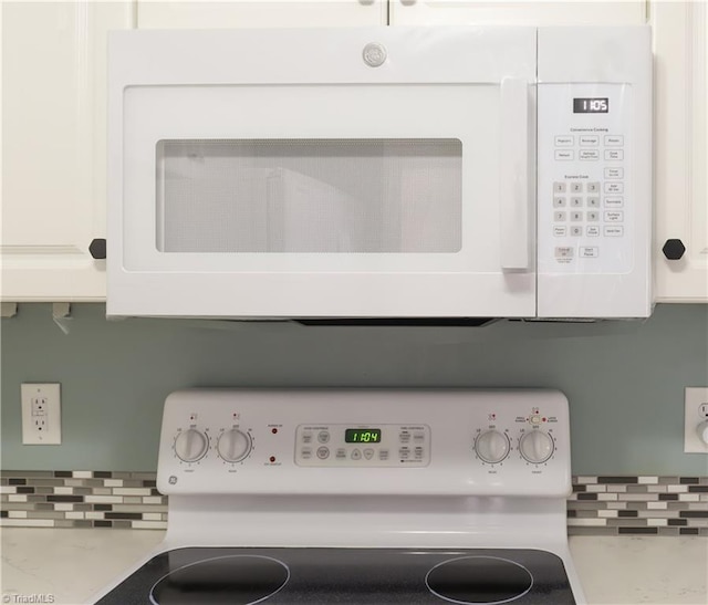 interior details featuring washer / clothes dryer, backsplash, white appliances, white cabinets, and light countertops