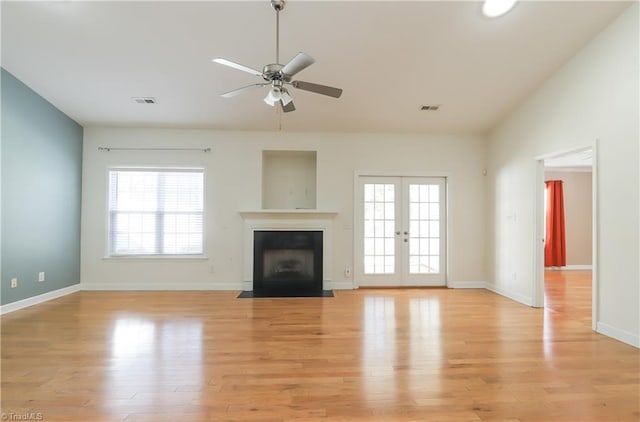 unfurnished living room with visible vents, a fireplace with flush hearth, light wood-style flooring, french doors, and ceiling fan