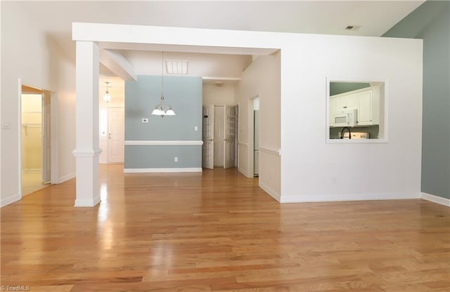 spare room with a notable chandelier, visible vents, light wood-type flooring, and baseboards